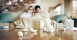 Sick, couple and tissue in home with fatigue, couch and disease from allergies with sneeze. Flu, li